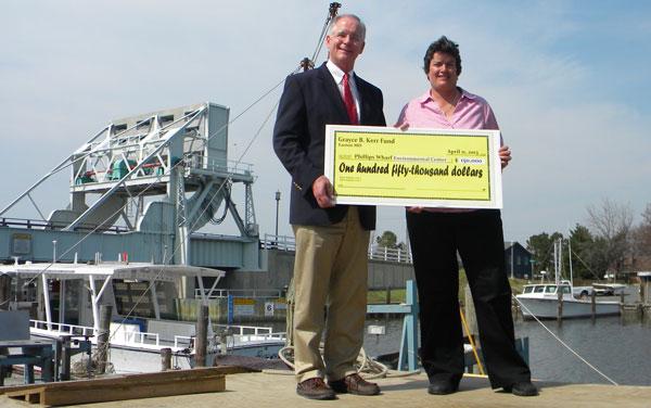  John Valliant, president of the Grayce B. Kerr Fund, presents a check for $150,000 to Kelley Cox, founder and executive director of Phillips Wharf Environmental Center in Tilghman.
