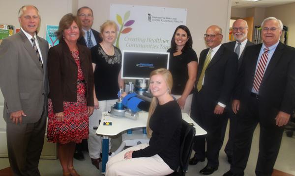 Appearing with the InMotion Upper Extremity Robot  (left to right) are Ken Kozel, president and CEO of UM Shore Regional Health; JoAnne Hahey, chief financial officer; Chris Parker, regional senior vice president, clinical services and chief nursing officer; Cassandra Kinser, occupational therapist; Sara Pender, occupational therapist (seated); Jessica Denny, physical therapist; Charles Capute, UM Memorial Hospital Foundation board chairman; William Roth, senior director, Comprehensive Rehabilitation Services; and Graham Lee, vice president for philanthropy. Missing from picture is Margaret Wood, physical therapist responsible for GaitRITE computerized gait analysis equipment. 